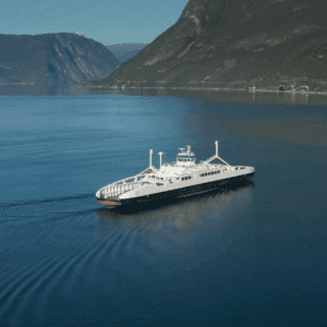 Färja på en fjord med berg i bakgrunden.
