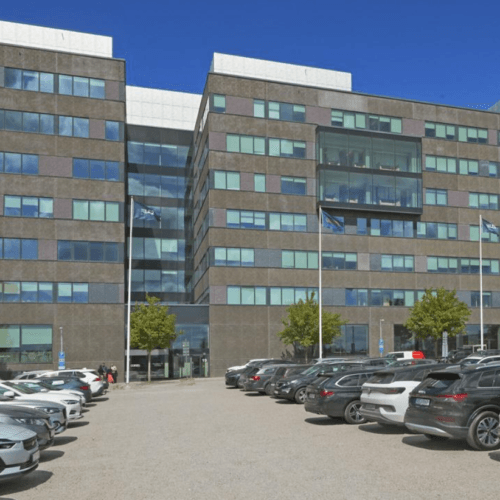 Modernt kontorshus med full parkeringsplats i solsken